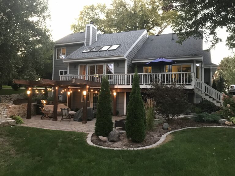 Two-story house with patio and outdoor lighting at dusk.